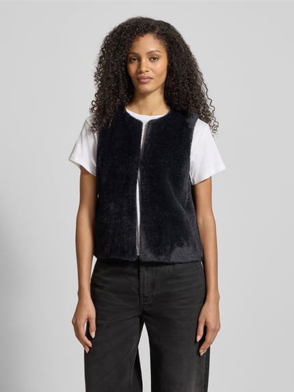 Frauenmodel trägt Regular Fit Weste in Kunstfell-Optik von Tom Tailor, Optik: Unifarben, Hakenverschluss, Label-Stitching-Applikation, Ganzkörperansicht von vorne.