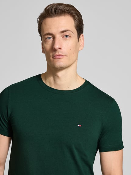 Mannelijk model draagt Slim Fit T-shirt uit katoenmix van Tommy Hilfiger, look: effen, logodetail, ronde hals, korte mouw, stretch; close-up van bovenlichaam
