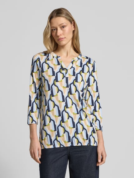 Frauenmodel trägt T-Shirt mit 3/4-Arm Modell 'FELICITY' von Soyaconcept, abstraktes Muster in Blau, Gelb und Weiß, Regular Fit, V-Ausschnitt, Baumwoll-Viskose-Mix, Nahaufnahme Oberkörper.