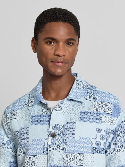 Männermodel trägt Regular Fit Overshirt im Allover-Look von Les Deux in Blau mit Kentkragen und Knopfleiste aus Baumwoll-Mix, Nahaufnahme Oberkörper. Rückenlänge bei Größe M: 69 cm.