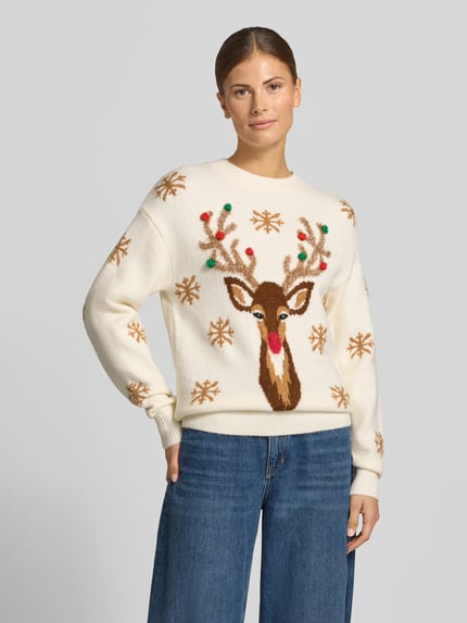 Frauenmodel trägt Strickpullover mit Motiv und Rundhalsausschnitt von Christian Berg Woman, cremefarbener Material-Mix mit Bommeln, Regular Fit, Motiv mit Rentier und Schneeflocken, Ganzkörperansicht von vorne.