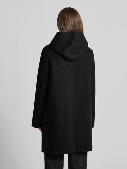 Frauenmodel trägt Mantel mit Kapuze und Eingrifftaschen von Apricot, Material-Mix in Schwarz, gerader Schnitt, Ganzkörperansicht Rückansicht.