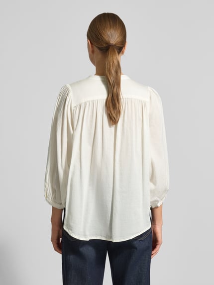 Frauenmodel trägt Regular Fit Bluse mit Rundhalsausschnitt Modell 'FAVIOLA' von 0039 Italy, reine Baumwolle, 3/4-Arm, Rückenlänge 65 cm, Ärmellänge 47 cm, in Creme mit lockerer Struktur, Ganzkörperansicht Rückansicht.