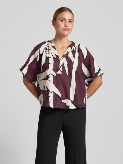 Frauenmodel trägt Boxy Fit Leinenbluse im Allover-Look von Christian Berg Woman in Lila-Weiß, V-Ausschnitt, Ganzkörperansicht von vorne.