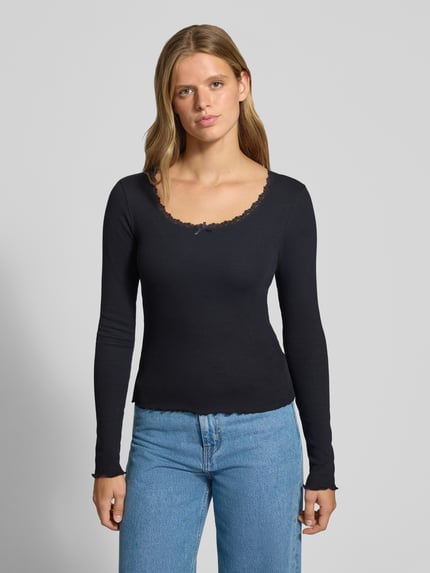 Frauenmodel trägt Longsleeve mit Spitzenbesatz und Rundhalsausschnitt von REVIEW aus Baumwoll-Elasthan-Mix in Schwarz, Ripp-Optik, Slim Fit, Ganzkörperansicht von vorne.