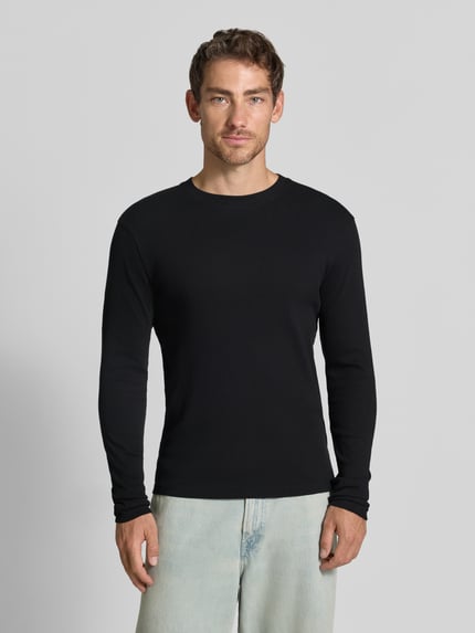 Mannenmodel draagt Slim Fit Longsleeve uit puur katoen Model 'Enil' van DRYKORN met structuurpatroon, zwarte kleur, ronde hals, voorkant volledige lichaamsweergave. Context: Heren shirt met lange mouwen van DRYKORN, puur katoen, slim fit, model 'Enil', structuurpatroon, ronde hals, ruglengte bij maat M: 67 cm, mouwlengte bij maat M: 69 cm.