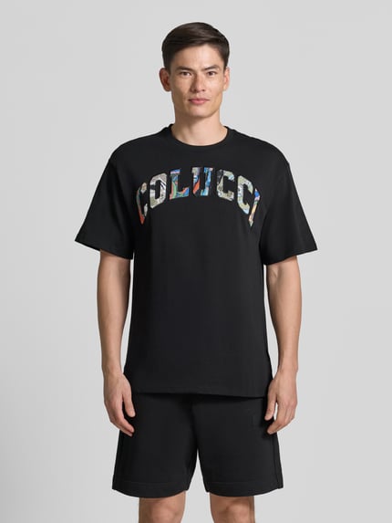 Männermodel trägt T-Shirt mit 1/2-Arm von COLUCCI in Schwarz, reine Baumwolle, gerader Schnitt, Rundhalsausschnitt, Ganzkörperansicht von vorne.