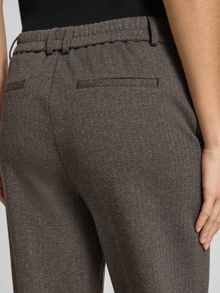 Frauenmodel trägt Stoffhose mit Umschlagabschluss von OPUS im unifarbenen Zickzackmuster, Baumwollmix, Nahaufnahme Rückansicht.