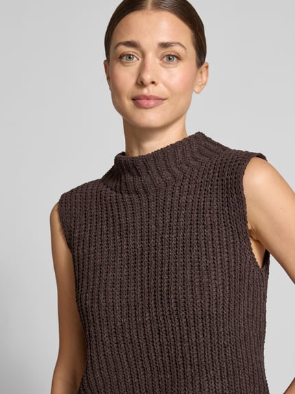 Frauenmodel trägt Slim Fit Pullunder mit Stehkragen von monari, Strick-Optik, braun, Kappärmel, Nahaufnahme Oberkörper.