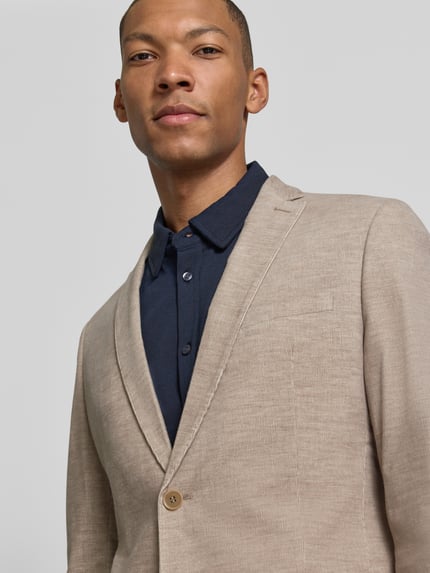 Männermodel trägt Slim Fit Sakko mit Pattentaschen von S. OLIVER BLACK LABEL, Melange-Optik, feines Webmuster, Nahaufnahme Oberkörper.