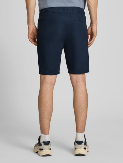 Männermodel trägt Regular Fit Bermudas aus Baumwoll-Leinen-Mix Modell 'LINUS' von Only & Sons, dunkelblau, unifarben, Ganzkörperansicht Rückansicht.