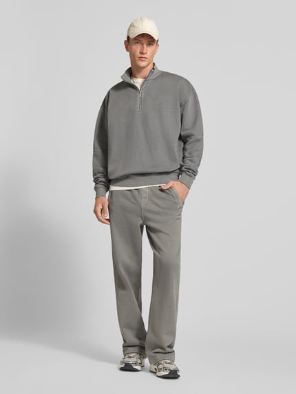 Männermodel trägt Relaxed Fit Sweatshirt aus Baumwoll-Mix von PEGADOR in Grau mit Troyer-Kragen und Logo-Stickerei, Ganzkörperansicht von vorne.