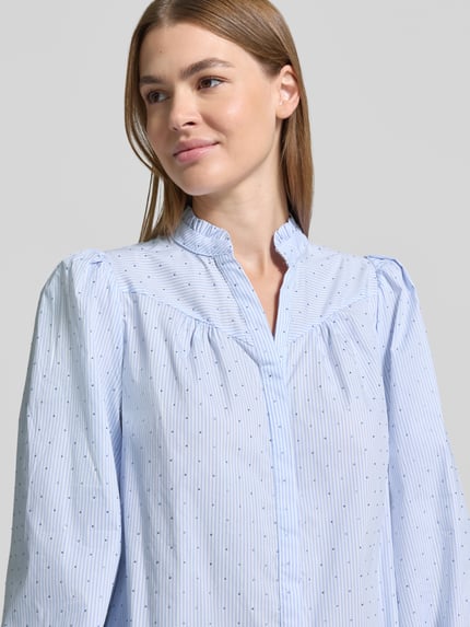 Frauenmodel trägt Regular Fit Bluse mit V-Ausschnitt Modell 'Astrida' von Neo Noir, hellblauer Baumwoll-Mix mit feinem Punktmuster, Nahaufnahme Oberkörper.