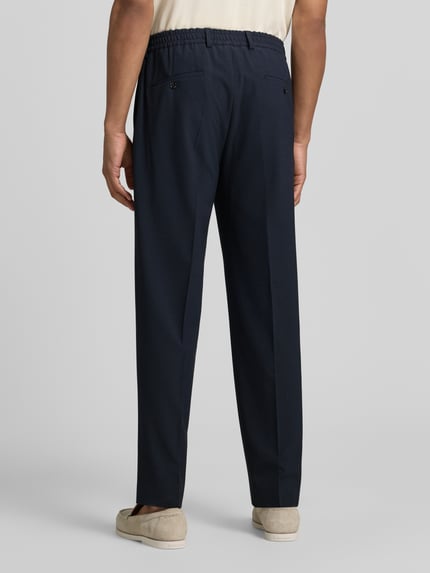 Mannenmodel draagt Stoffen broek met persplooien model 'River' van JOOP! collectie, materiaalmix met viscose, straight fit, elastische band met knoop- en ritssluiting, steekzakken, strookzakken aan de achterkant, bandwijdte maat 50: 44 cm, binnenbeenlengte maat 50: 77 cm, donkerblauw, gladde stof, geheel zicht van achteren