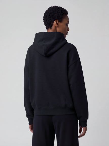 Männermodel trägt Oversized Fit Hoodie aus reiner Baumwolle von Nike in Schwarz, unifarben, strukturierte Optik, Ganzkörperansicht Rückansicht.