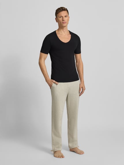 Męski model nosi T-Shirt mit V-Ausschnitt od MCNEAL, bawełniany miks ze stretchem, krój regular fit, czarny, widok całej sylwetki z przodu.