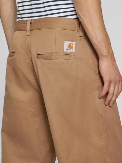 Männermodel trägt Relaxed Fit stoffen broek met katoenmix Model 'Brady' van Carhartt Work In Progress, Materiaalmix, steekzakken, riemlussen, knoop- en ritssluiting, achterzakken, bandwijdte maat M 46 cm, binnenbeenlengte maat M 74 cm, detailopname rugaanzicht.