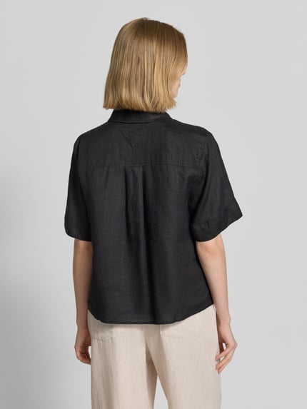 Modelka nosi Regular Fit Leinenbluse mit Logo-Stitching od Tommy Hilfiger, czarna, lniana, z krótkim rękawem, jednokolorowa, widok całej sylwetki z tyłu.