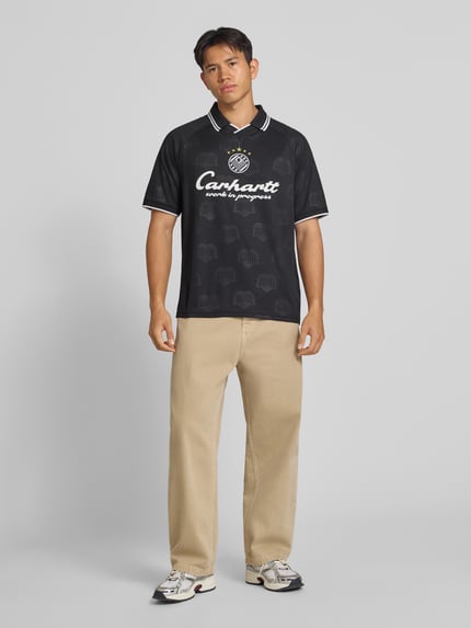 Männermodel trägt Funktionsshirt mit Logo Modell 'Terrace' von Adidas, schwarz mit weißem Print, Regular Fit, Rundhalsausschnitt, Ganzkörperansicht von vorne, Rückenlänge bei Größe M: 71 cm.