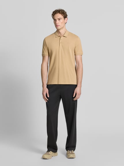 Męski model nosi koszulkę polo o kroju regular fit z czystej bawełny model 'DONOS222' od HUGO w kolorze beżowym, widok całej sylwetki z przodu.
