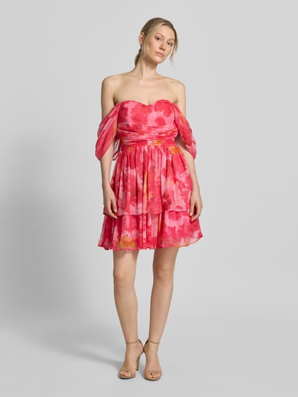 Modelka nosi sukienkę koktajlową 'Cocktailkleid im Off-Shoulder-Design' od LACE & BEADS, taliowany krój, sukienka mini, wzór na całej powierzchni, krój z odkrytymi ramionami, długość tyłu w rozmiarze S: 67 cm, szerokość w rozmiarze S: 45 cm, długość rękawów w rozmiarze S: 43 cm, intensywny różowy kolor z pomarańczowymi i czerwonymi akcentami, delikatna tekstura materiału, widoczne warstwowanie, widok całej sylwetki z przodu.