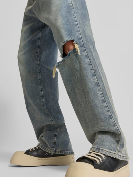 Männermodel trägt Straight Fit Jeans im Destroyed-Look von Don't Waste Culture, blauer Baumwoll-Elasthan-Mix, Nahaufnahme Bein, KI-modifiziertes Bild