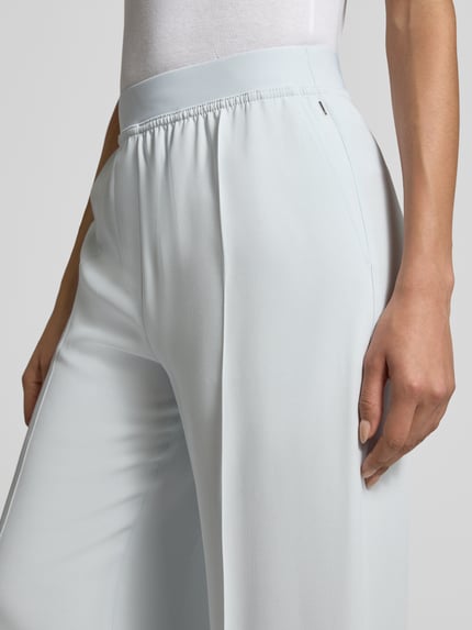 Frauenmodel trägt Weite Hose aus reiner Viskose Modell 'TIANA10' von BOSS in Hellblau, unifarben, elastischer Bund, seitliche Eingrifftaschen, Nahaufnahme Hüfte.