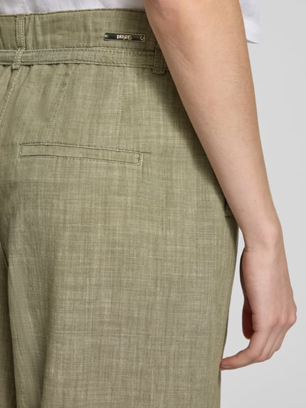 Frauenmodel trägt Wide Fit Stoffhose mit Bügelfalten Modell 'Livia' von Angels aus Reine Baumwolle, grün, Nahaufnahme Hüfte Rückansicht.