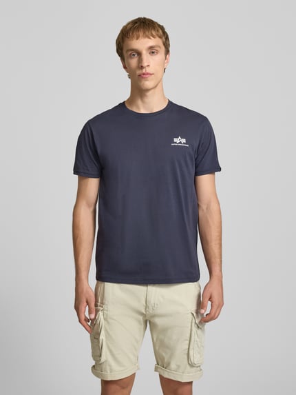 Männermodel trägt T-Shirt mit Logo und Rundhalsausschnitt von Alpha Industries in Dunkelblau, Reine Baumwolle, Regular-Fit, Rückenlänge 67 cm, Ganzkörperansicht von vorne.
