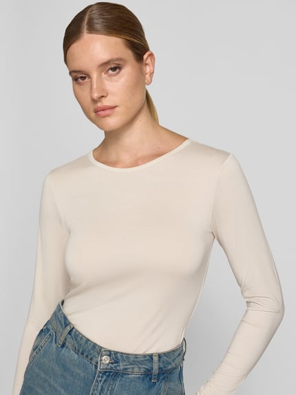 Vrouwenmodel draagt shirt met lange mouwen van mix van viscose en elastaan Model 'Liana' van FREE/QUENT, slim fit, ronde hals, ruglengte maat S 59 cm, lichte kleur, gladde textuur, Ganzkörperansicht van voren.