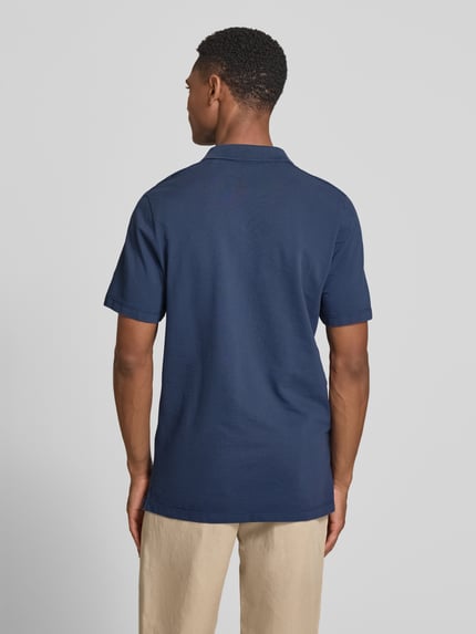 Männermodel trägt Regular Fit Poloshirt aus reiner Baumwolle von s.Oliver RED LABEL, unifarben in Dunkelblau, Piqué-Struktur, Ganzkörperansicht Rückansicht.