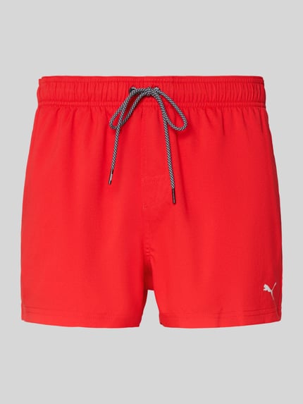 Produktfoto, Badehose mit Seitentaschen und Klettverschlusstasche hinten von PUMA in leuchtendem Rot, elastischer Bund, Regular Fit, auf weiß-grauem Hintergrund.