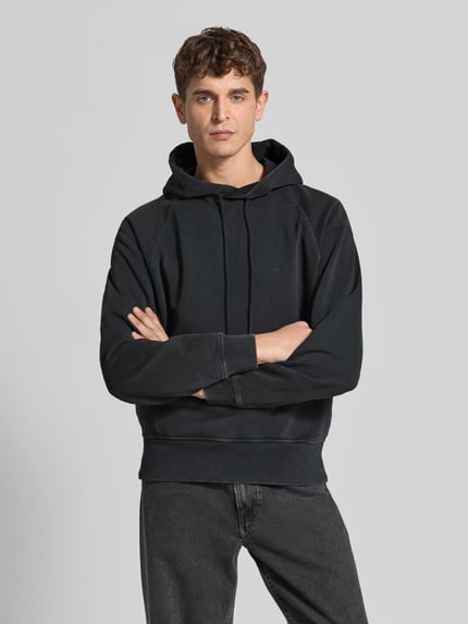 Męski model nosi Regular Fit Hoodie aus reiner Baumwolle od Closed, czarny, krój regular fit, kaptur z tunelem, kieszeń kangurka, elastyczne wykończenia, długość tyłu w rozmiarze M: 62 cm, bawełna, zdjęcie z przodu w ujęciu na górną część ciała.