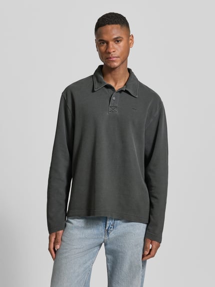 Männermodel trägt Loose Fit Poloshirt aus Baumwolle Modell 'Thiago' von Wood Wood in Dunkelgrau, Obermaterial matt, Ganzkörperansicht von vorne.
