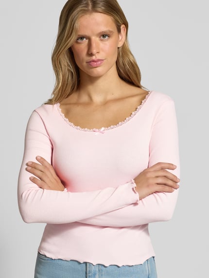 Frauenmodel trägt Longsleeve mit Spitzenbesatz und Rundhalsausschnitt von REVIEW in Rosa, Ripp-Optik, Slim Fit, Ganzkörperansicht von vorne.