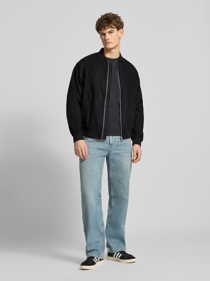 Mannelijk model draagt Bomberjacke mit Reißverschluss van REVIEW in zwart, regular fit, ribboorden, opstaande kraag, rits, steekzakken, label-stitching, ruglengte 68 cm, schouderbreedte 43 cm, borstwijdte 55 cm, mouwlengte 63 cm; kleuren zwart en lichtblauw, rechte vormen, gladde en geribde texturen, full-body voetaanzicht.