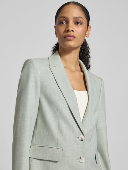 Frauenmodel trägt Regular Fit Blazer aus Viskose-Mix mit Reverskragen von Comma, zartgrün, Pattentaschen, 2-Knopfleiste, Nahaufnahme Oberkörper.