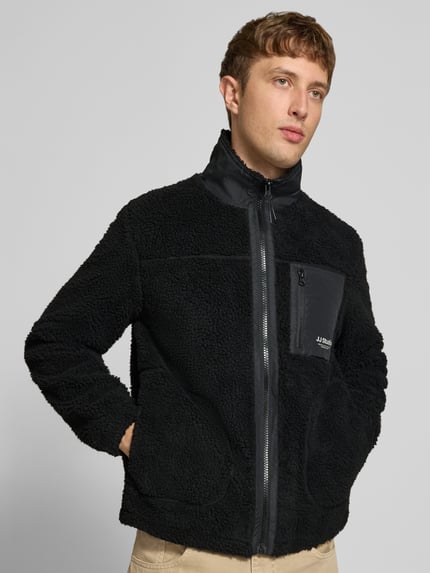 Männermodel trägt Fleecejacke mit Stehkragen Modell 'SOHO' von JACK & JONES, Teddyfell, Schwarz, sichtbare Reißverschlüsse, Nahaufnahme Oberkörper.