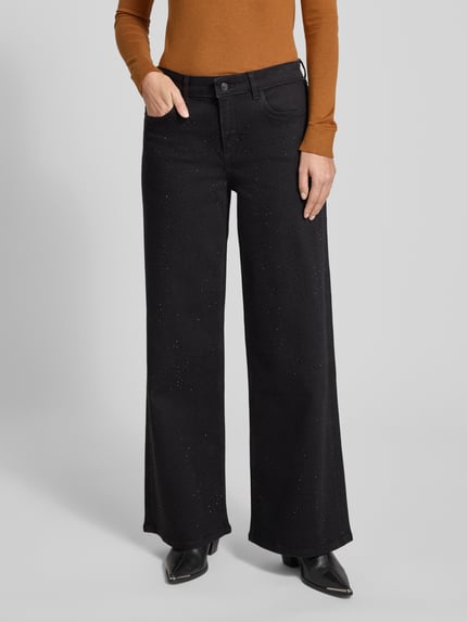 Frauenmodel trägt Relaxed Fit Jeans mit 5-Pocket-Design von comma, schwarzer Baumwoll-Mix, lockerer Schnitt, Ziersteinbesatz, Nahaufnahme Oberkörper.