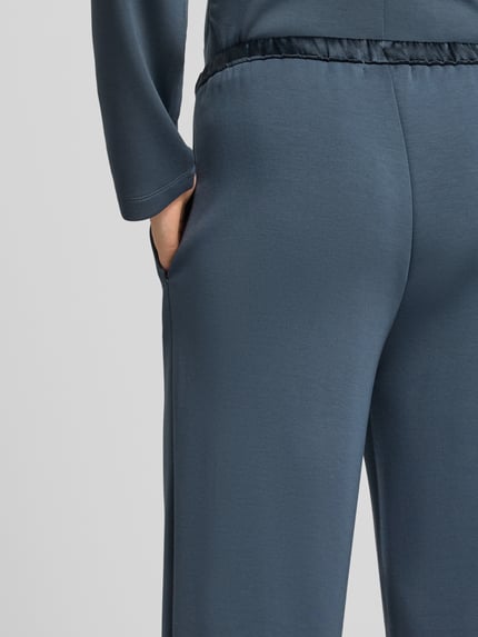 Frauenmodel trägt Sweatpants mit elastischem Bund und Eingrifftaschen von Scotch & Soda, Material-Mix mit Modal-Anteil, weites Bein, Nahaufnahme Hüfte.