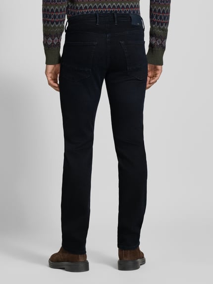 Männermodel trägt Slim Fit Jeans mit Dark-Wash-Optik Modell 'Arne' von MAC, 5-Pocket-Design, Ganzkörperansicht Rückansicht.