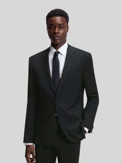 Mężczyznamodel nosi Slim Fit Anzugsakko aus Woll-Mix Modell 'ARTI' von HUGO w kolorze melanżowym, krój slim fit, długo rękawa, patki i listwa na piersi, wełniany materiał. Ganzkörperansicht von vorne.