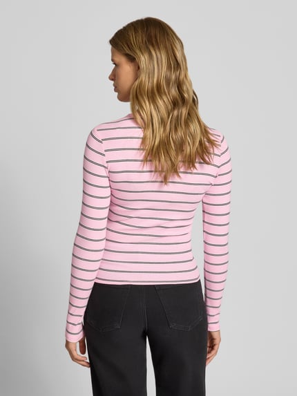 Frauenmodel trägt Slim Fit Langarmshirt aus Baumwoll-Mix von Tommy Jeans in Rosa mit schwarzen Streifen, Damen Langarmshirt, Ganzkörperansicht Rückansicht.
