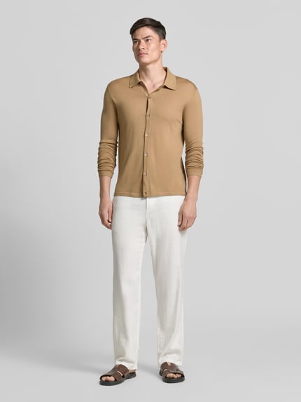 Męski model nosi Regular Fit Strickjacke aus Wolle Modell 'Verklin' od Tiger Of Sweden, kołnierzyk typu kent, listwa guzikowa, kardigan rozpinany, czysta wełna, krój regular fit, długość tyłu w rozmiarze M: 71 cm, długość rękawów w rozmiarze M: 65 cm, kolor beżowy, gładka faktura, całkowity widok z przodu.