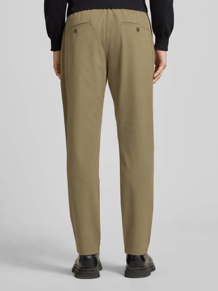 Männermodel trägt Stoffhose mit elastischem Bund von MCNEAL, Material-Mix mit Viskose-Anteil, lockerer Schnitt, Ganzkörperansicht Rückansicht.
