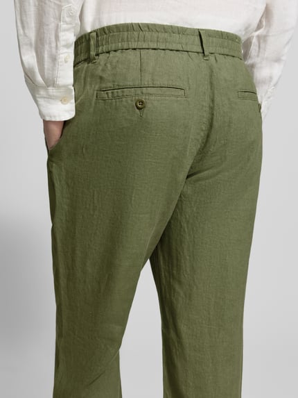 Männermodel trägt Regular Fit Leinenhose mit elastischem Bund von Gant, reine Leinen, grün, feine Struktur, Ganzkörperansicht Rückansicht. Bundweite 44 cm, Innenbeinlänge 80 cm, Schnürung.