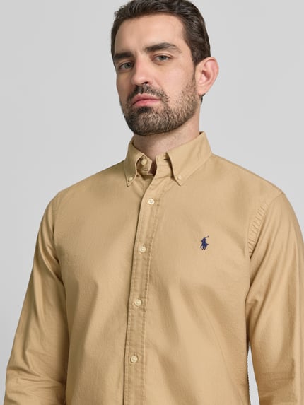 Männermodel trägt Freizeithemd mit Knopfleiste von Polo Ralph Lauren in Beige, reine Baumwolle, Button-Down-Kragen, Label-Stitching, Nahaufnahme Oberkörper.