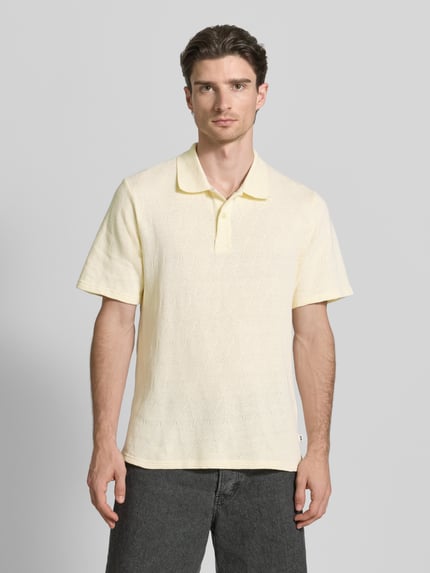 Männermodel trägt Regular Fit Poloshirt mit Knopfleiste Modell 'Gabriel' von Wood Wood, Reine Baumwolle, Herren, Ganzkörperansicht von vorne. Rückenlänge bei Größe M: 70 cm. Helle, leicht gelbliche Farbe, dezente Struktur.