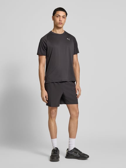 Męski model nosi T-Shirt mit Logo und Rundhalsausschnitt von PUMA PERFORMANCE, czarny, krój regular fit, logo, długość pleców 70 cm w rozmiarze M, całopostaciowy widok z przodu