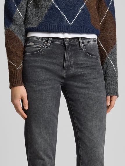 Frauenmodel trägt Jeansy z 5 kieszeniami Model 'Kate' od G-Star Raw, mieszanka bawełny i elastanu, prosty krój, detal z logo, mankiety, zapięcie na guzik i zamek, kolor szary, tekstura denim. Nahaufnahme obszaru bioder i ud.